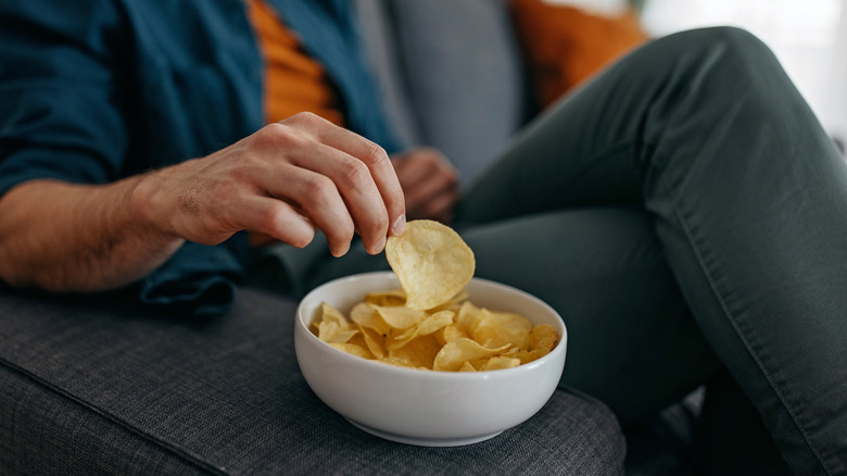 Person eating chips on couch