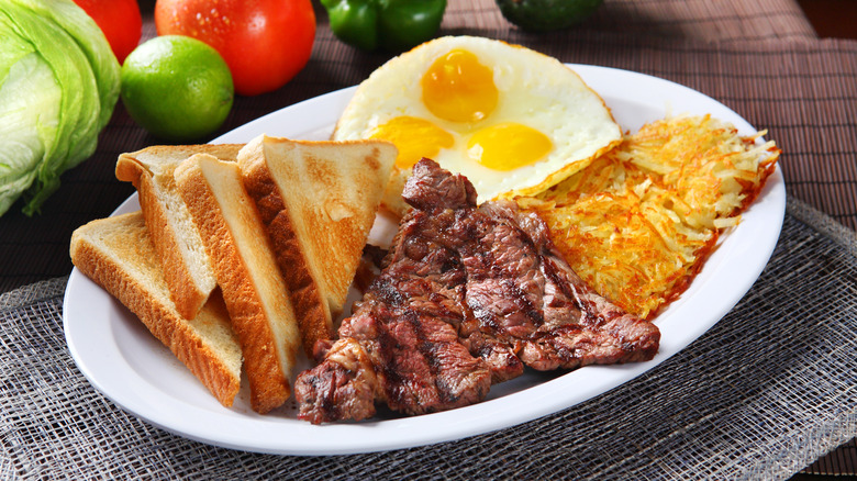 Steak, fried eggs, toast and hash browns on a plate