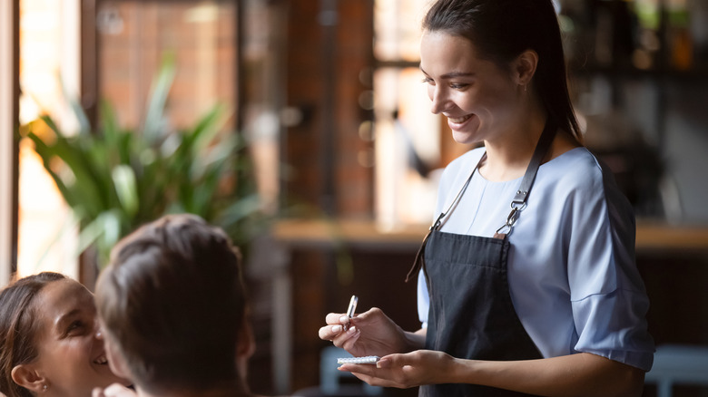 Smiling young waitress taking food orders