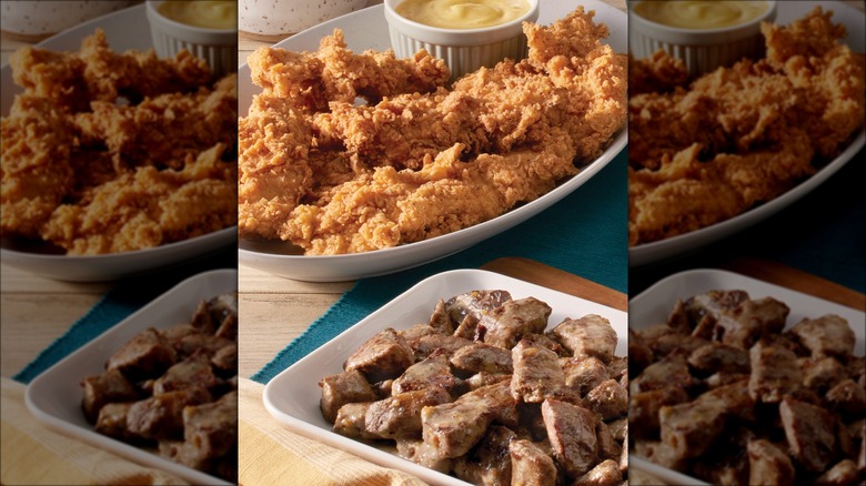 fried chicken and steak tips in serving dishes on table