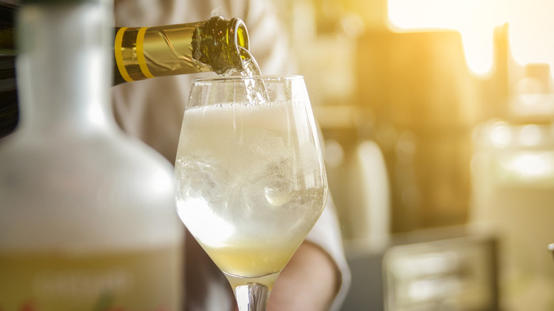 A person pours sparkling wine into a glass