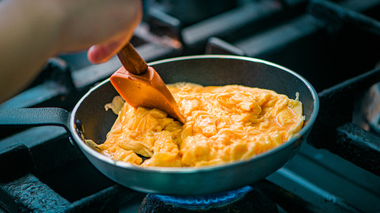 scrambling eggs with spatula in pan