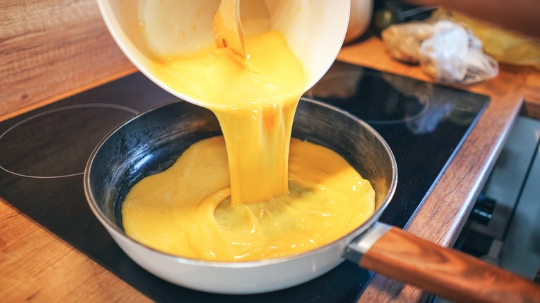 pouring beaten eggs into pan