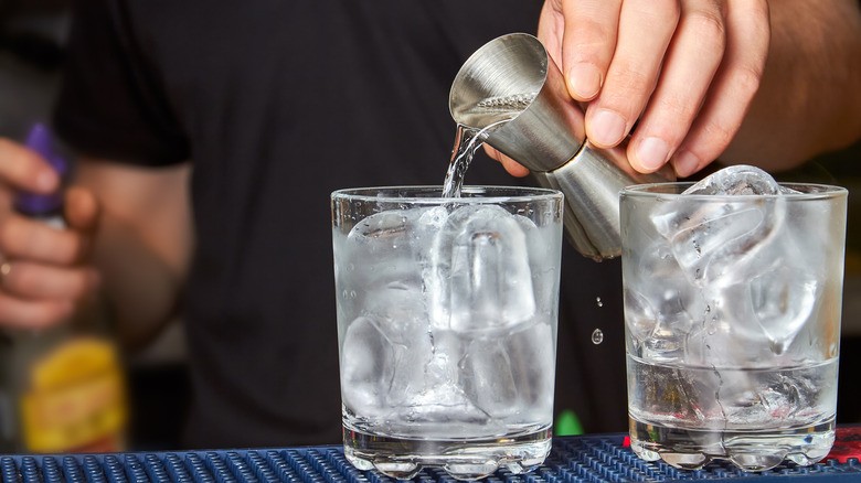 bartender pouring shot of gin into glass