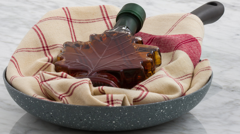 Maple syrup bottle in pan with towel