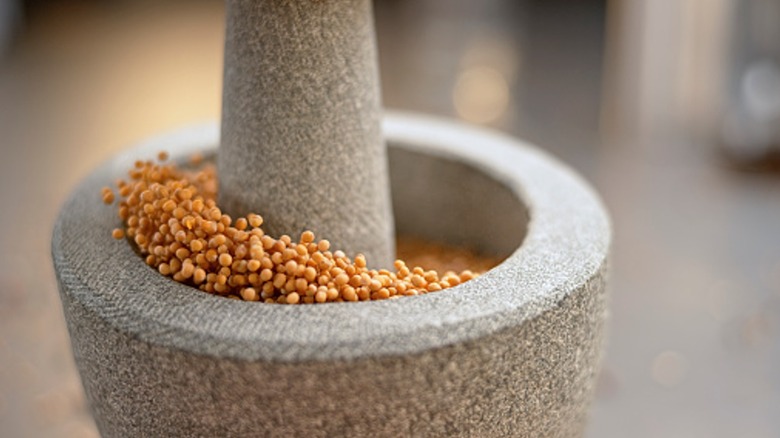 mortar and pestle grinding mustard seeds