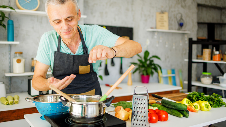 Person seasoning soup in pot