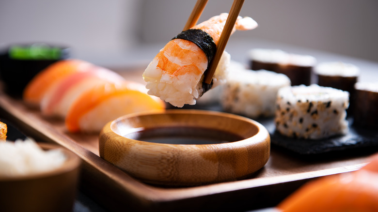 sushi being dipped in soy sauce