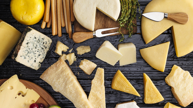 variety of cheeses with two cheese knives