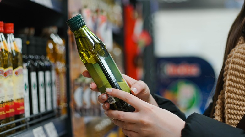 Person holding olive oil bottle