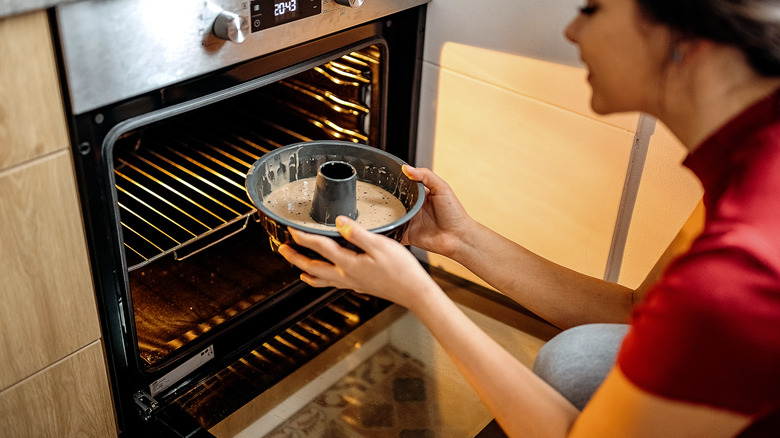 Woman placing Bundt cake in oven