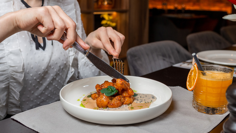 restaurant patron eating meal with a knife and fork 