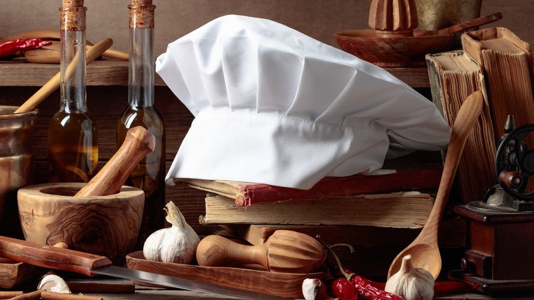 Chef's hat with cookbooks and cooking utensils