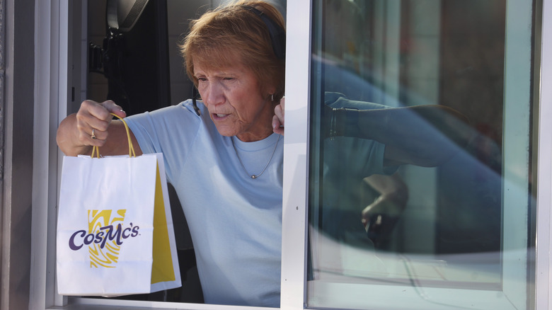 Drive-thru worker handing a CosMc's bag out of the drive-thru window