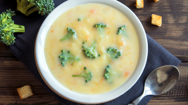 A bowl of broccoli and cheese soup on a blue napkin