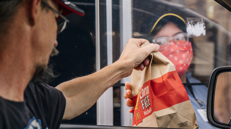 A McDonald's employee handing a drive-thru customer their food