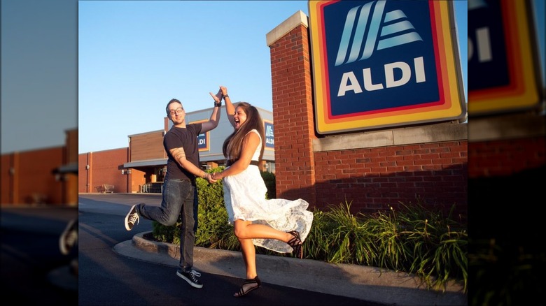 Michael Hurd and Jessica Bojanowski jumping outside an Aldi store