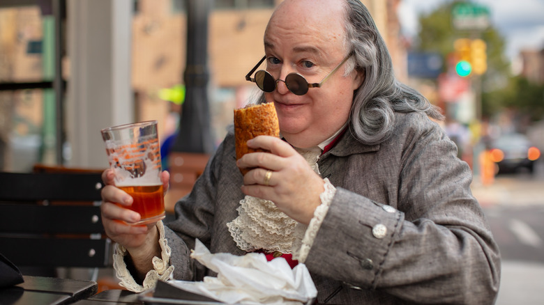 Ben Franklin cosplayer with a cheeseteak and beer