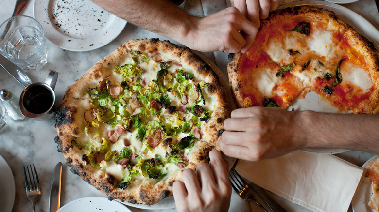 hands grabbing pizza slices