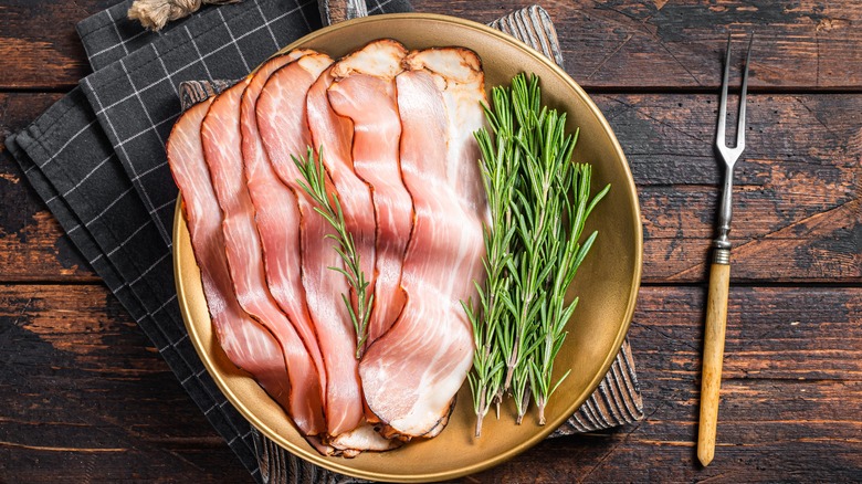 Baked bacon strips on a plate with rosemary