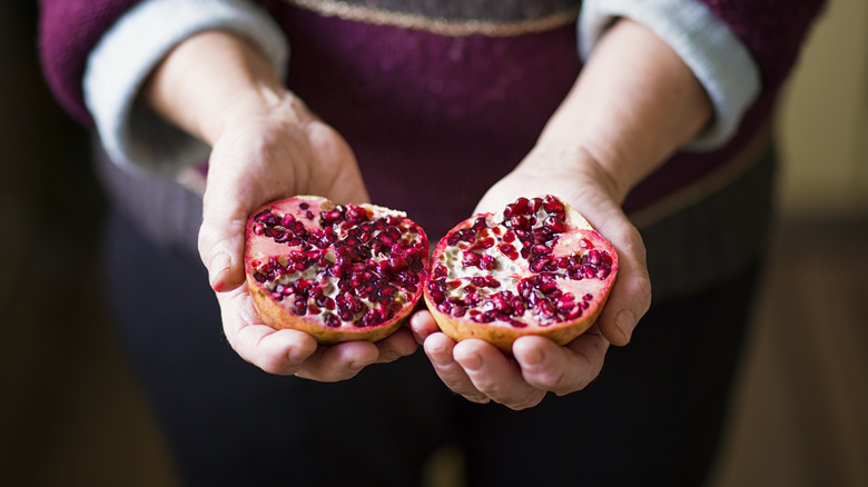 hands holding split pomegranates