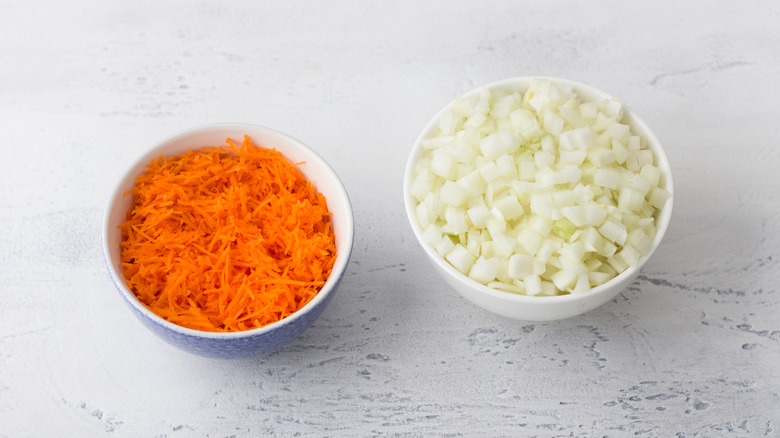 Grated carrots and finely chopped onions in white bowls