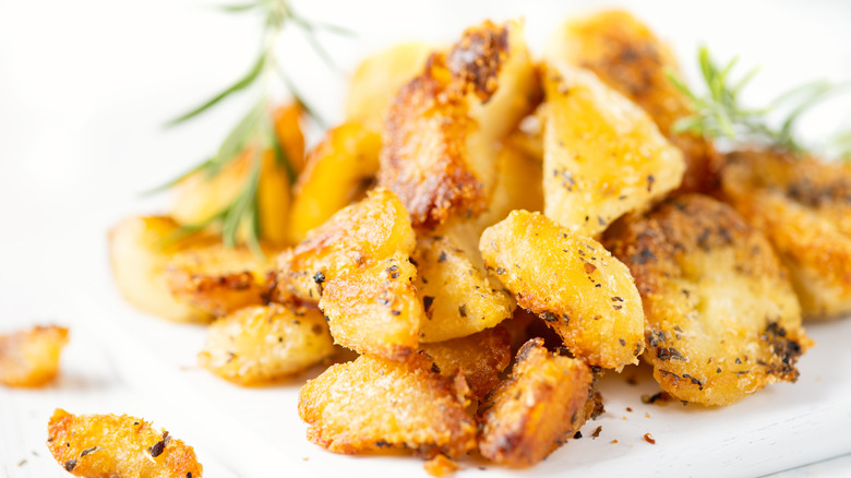 Duck fat potatoes with herbs on white plate 