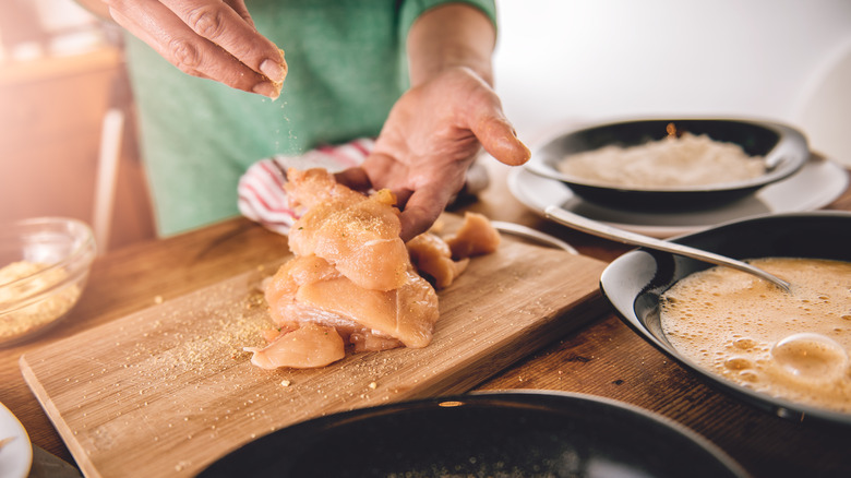 chef seasoning chicken by hand