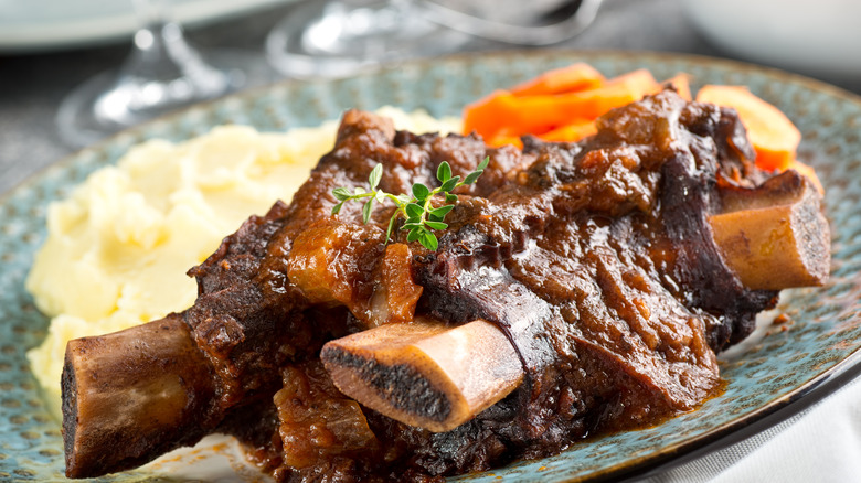 short ribs on a plate with mash and sliced carrots