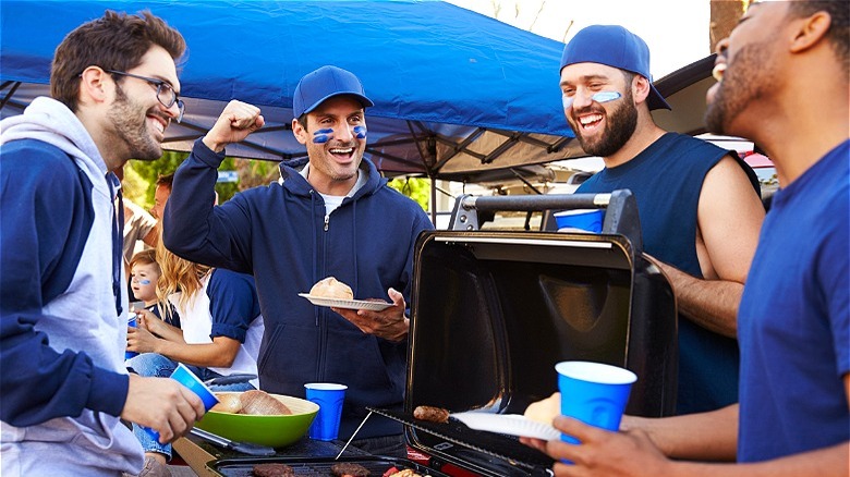 Sports fans in blue around portable grill