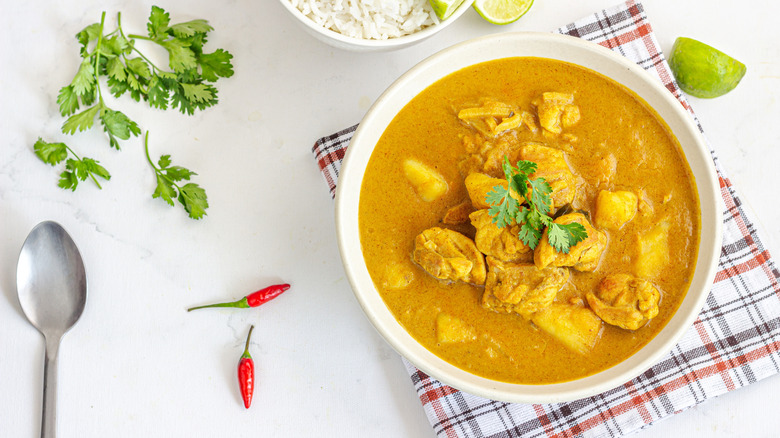 Bowl of Thai yellow curry with herbs, chilies, and spoon