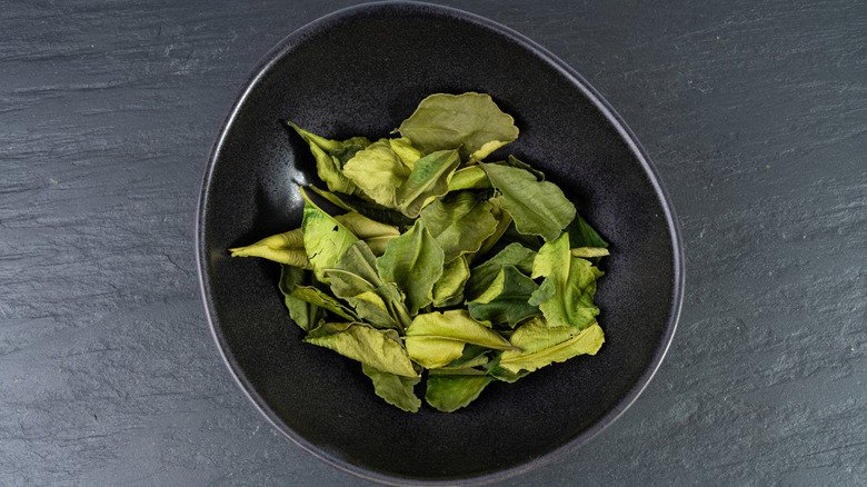 Black bowl full of dried Makrut lime leaves