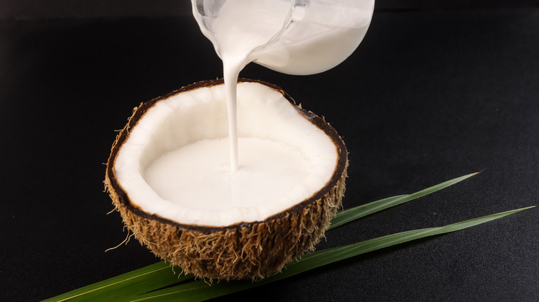 Halved coconut, with coconut milk being poured into it