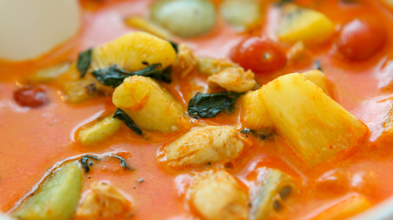 Vegetables submerged in red curry sauce