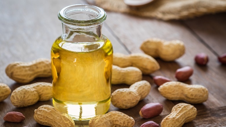 a bottle of peanut oil surrounded by peanuts