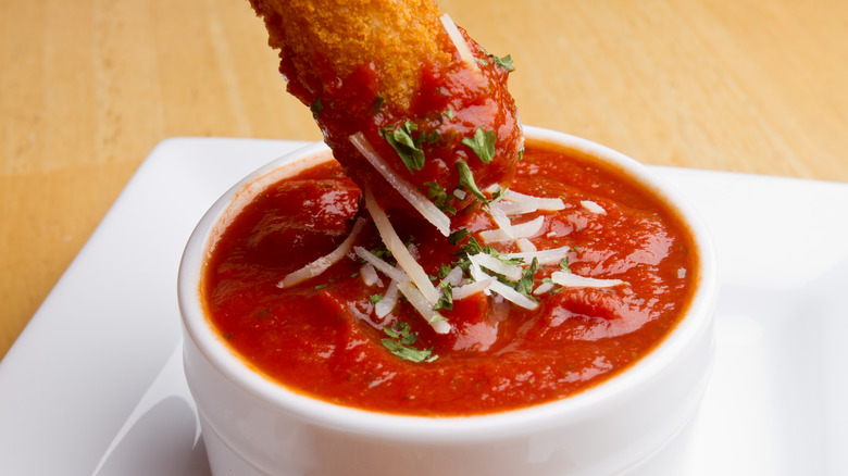 Dipping mozzarella stick in marinara