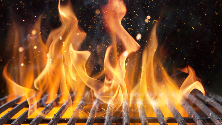 Orange flames rising through grill grates