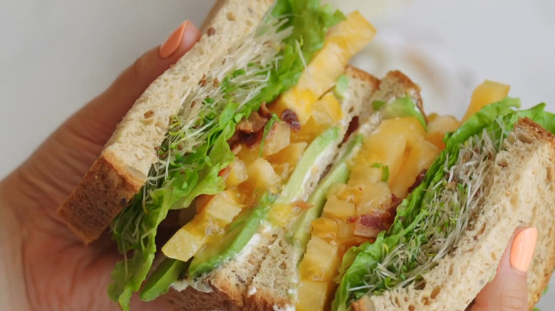 hands holding BLT with untoasted bread