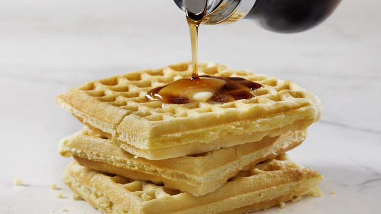 syrup being poured onto waffles