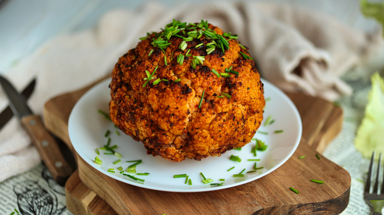 Whole roasted cauliflower covered in green onions