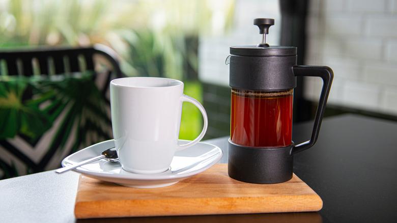 French press coffee maker with white mug