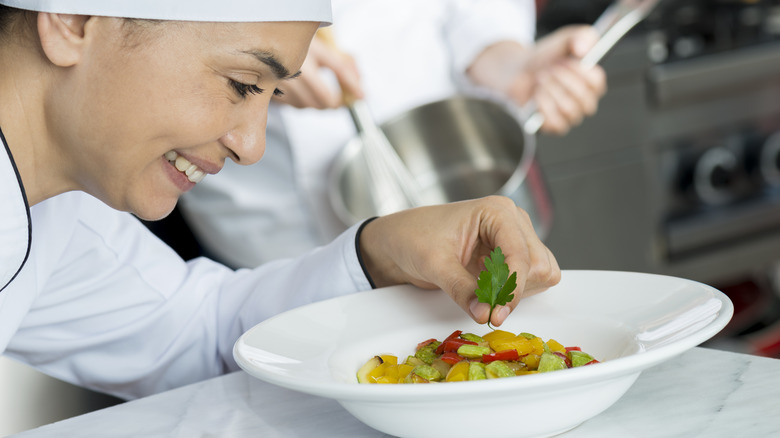 Chef garnishing dish with parsley