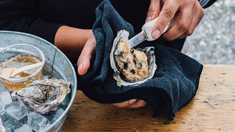 Person shucking an oyster with a knife