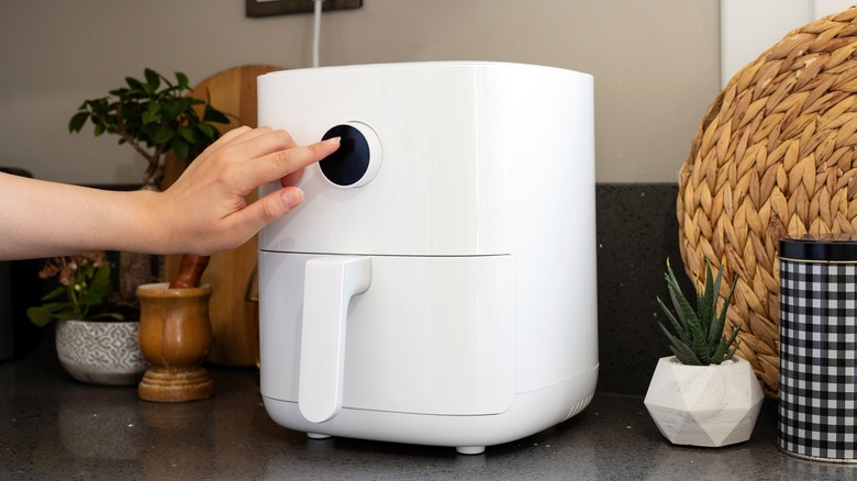 hand pushing air fryer button