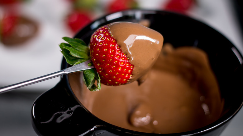 Chocolate-covered strawberry on prong over chocolate fondue