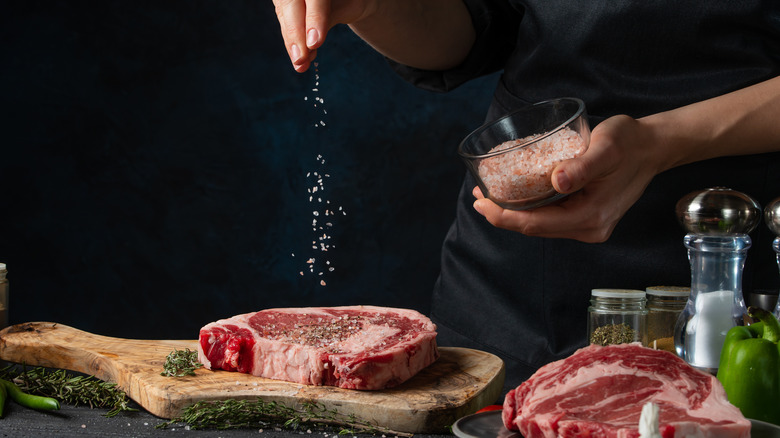 Salting steak on cutting board