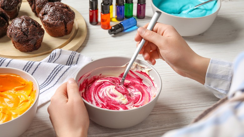 cook stirring food coloring into frosting