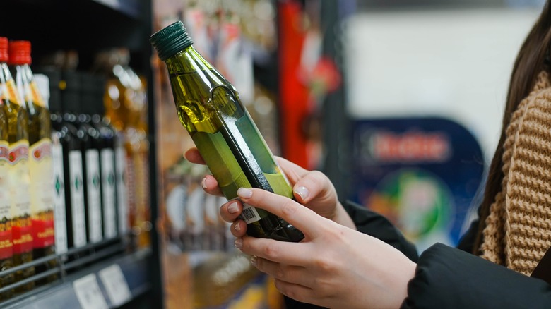 shopper examining bottle of olive oil