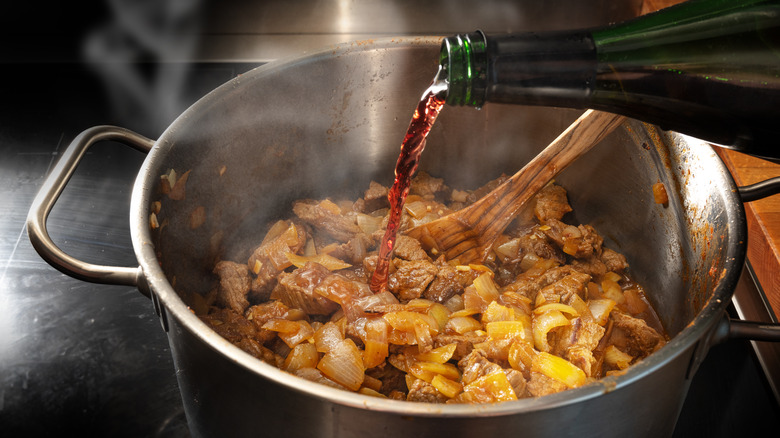 Person pouring red wine into pot 