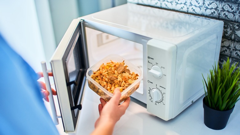 person placing leftovers in microwave